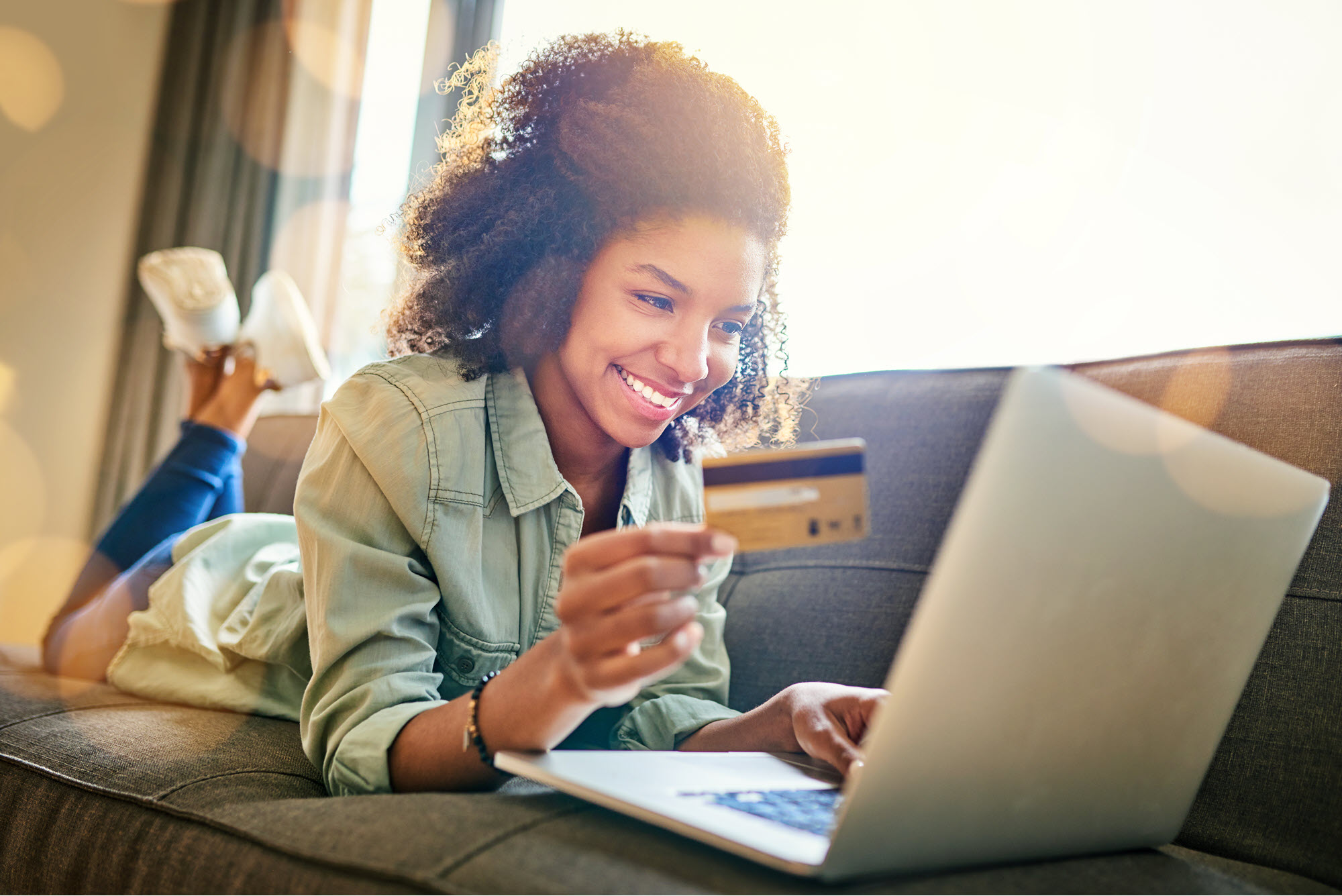 High School girl in front of a computer with a debit card in her hand